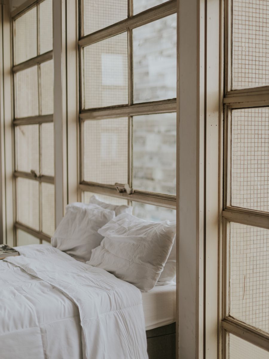 A cozy bedroom corner with tall vintage windows and morning light.