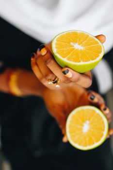Vibrant close-up of hands holding freshly cut orange halves, showcasing bright citrus colors.