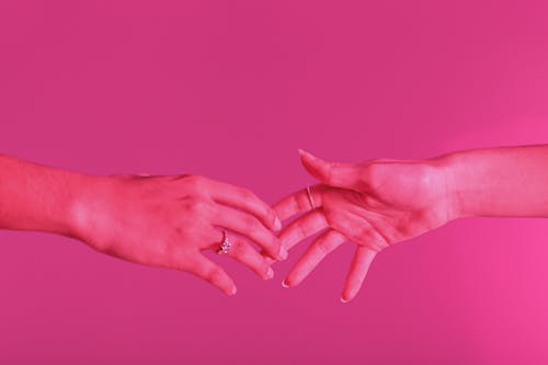 Фотография касания рук на розовом фоне