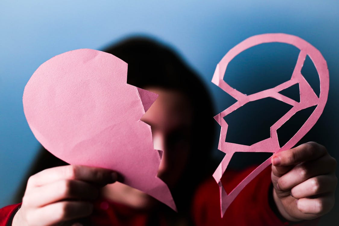 Free Person Holding Two Parts of Paper Heart Stock Photo
