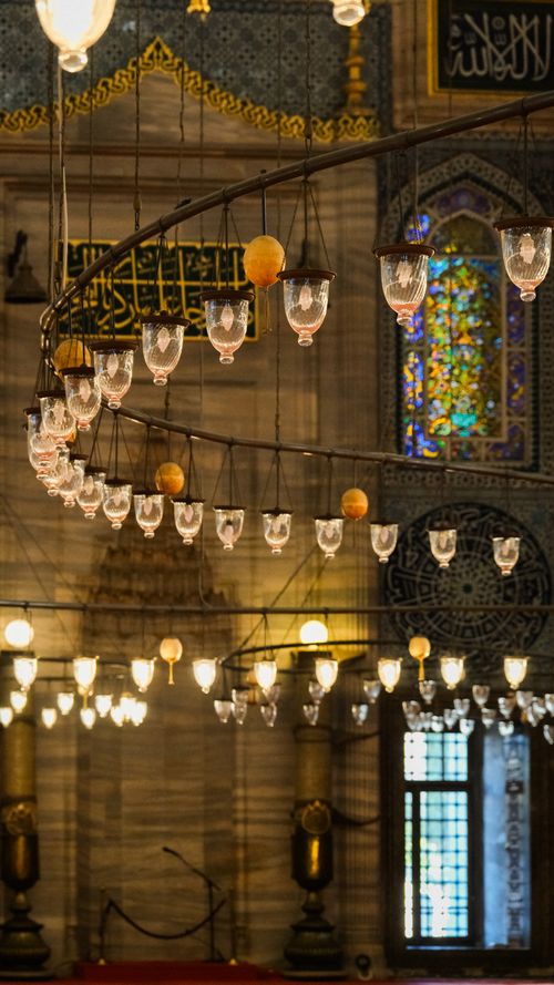 Free A stunning view of ornate lighting fixtures inside an Istanbul mosque, featuring stained glass windows. Stock Photo
