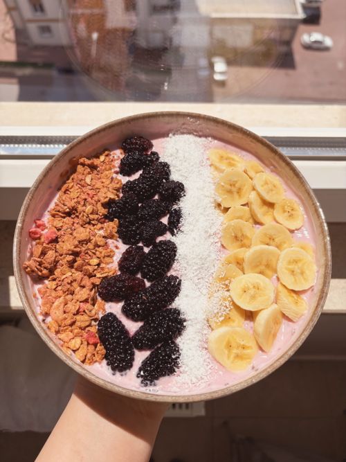 Free Delicious pink smoothie bowl topped with granola, blackberries, coconut, and banana slices. Stock Photo