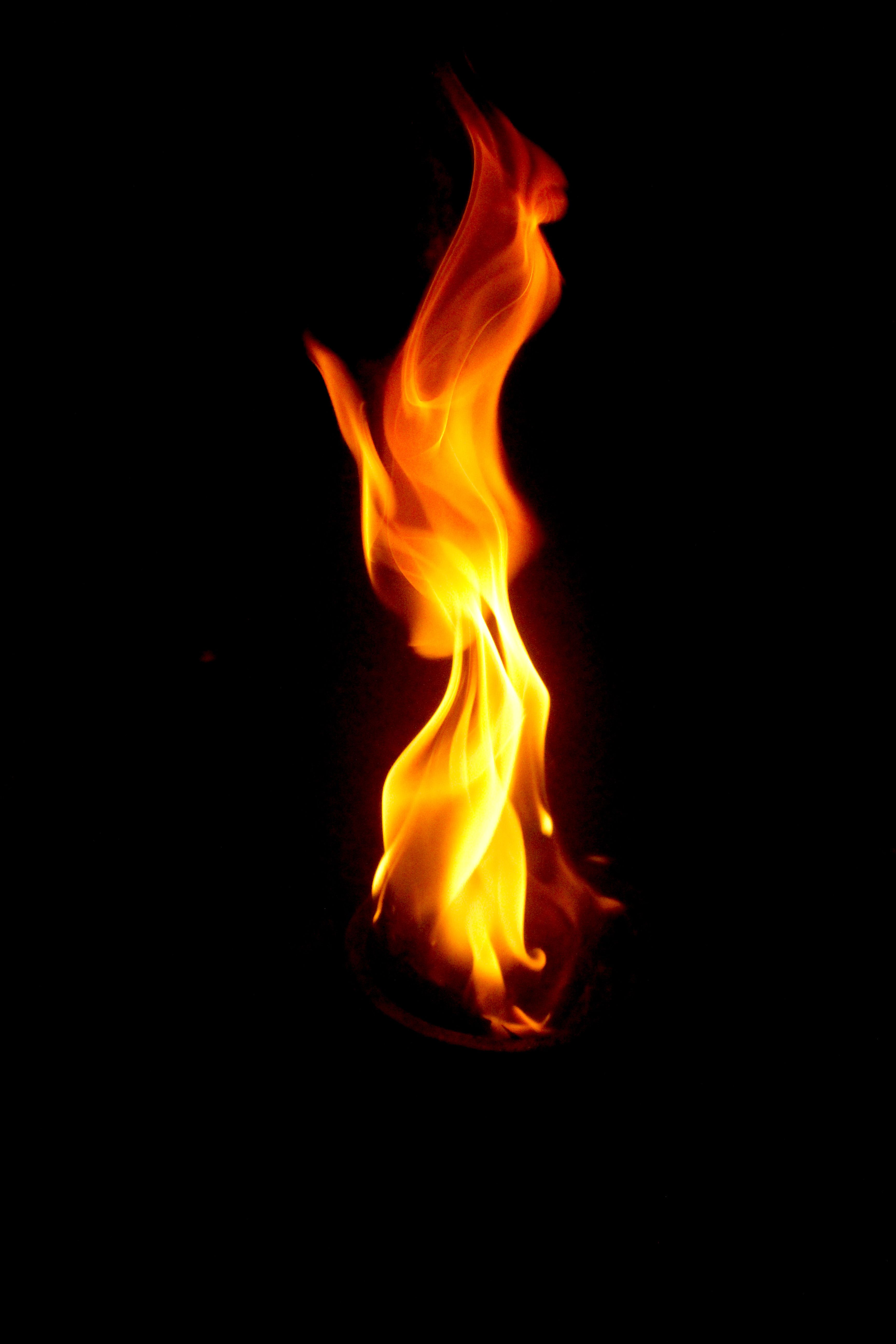 Dramatic close-up of a vibrant flame in darkness, showcasing mesmerizing patterns.