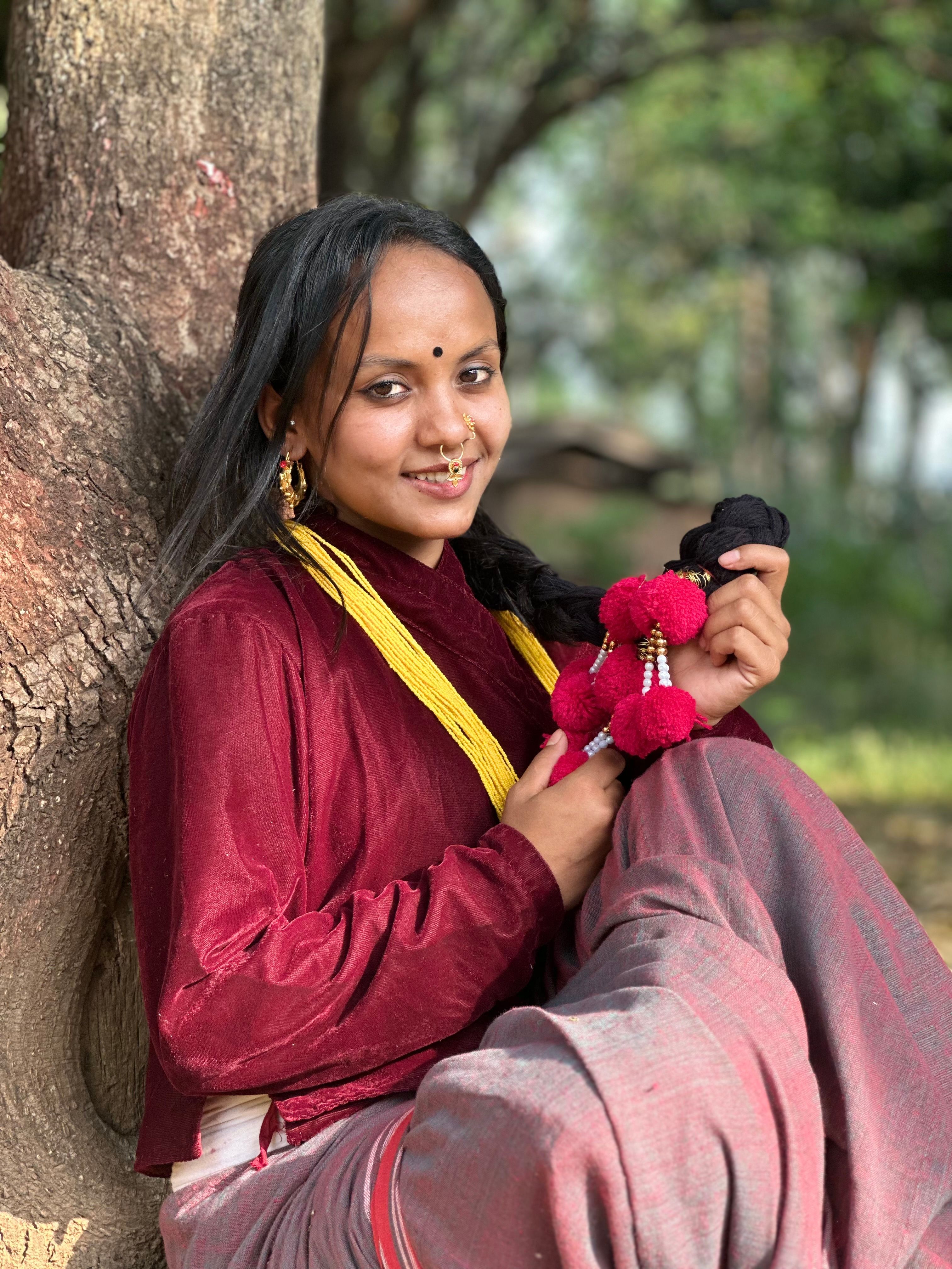 A young Nepali woman in traditional attire sitting outdoors, embracing her cultural heritage.