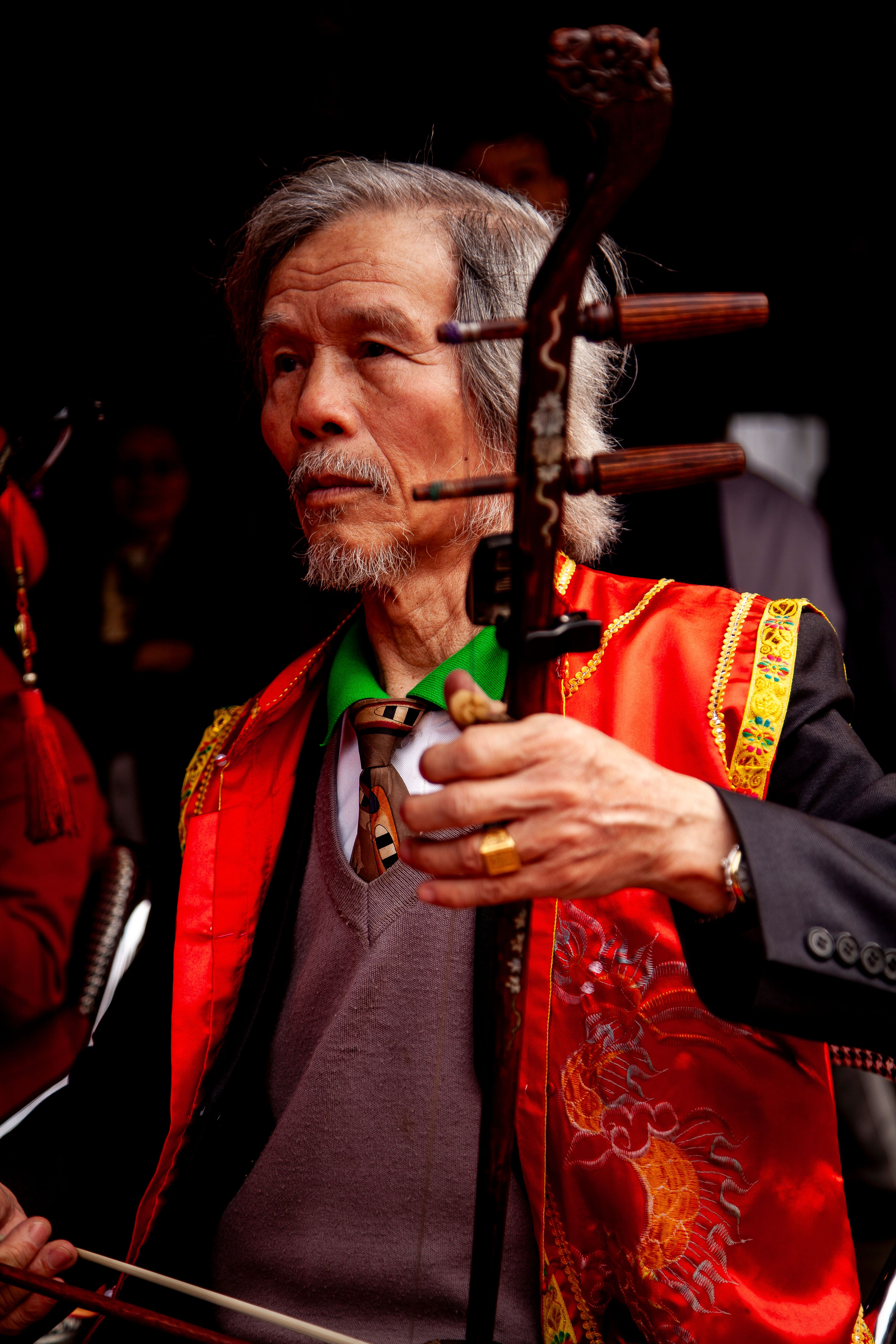Elderly musician in Hà Nội, Vietnam, performs with Đàn Nhị, showcasing Vietnamese culture.