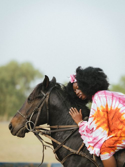 Free A young woman in vibrant attire riding a horse in a natural outdoor setting. Stock Photo