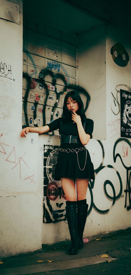Free Fashionable woman in urban setting with graffiti background demonstrating modern street style. Stock Photo