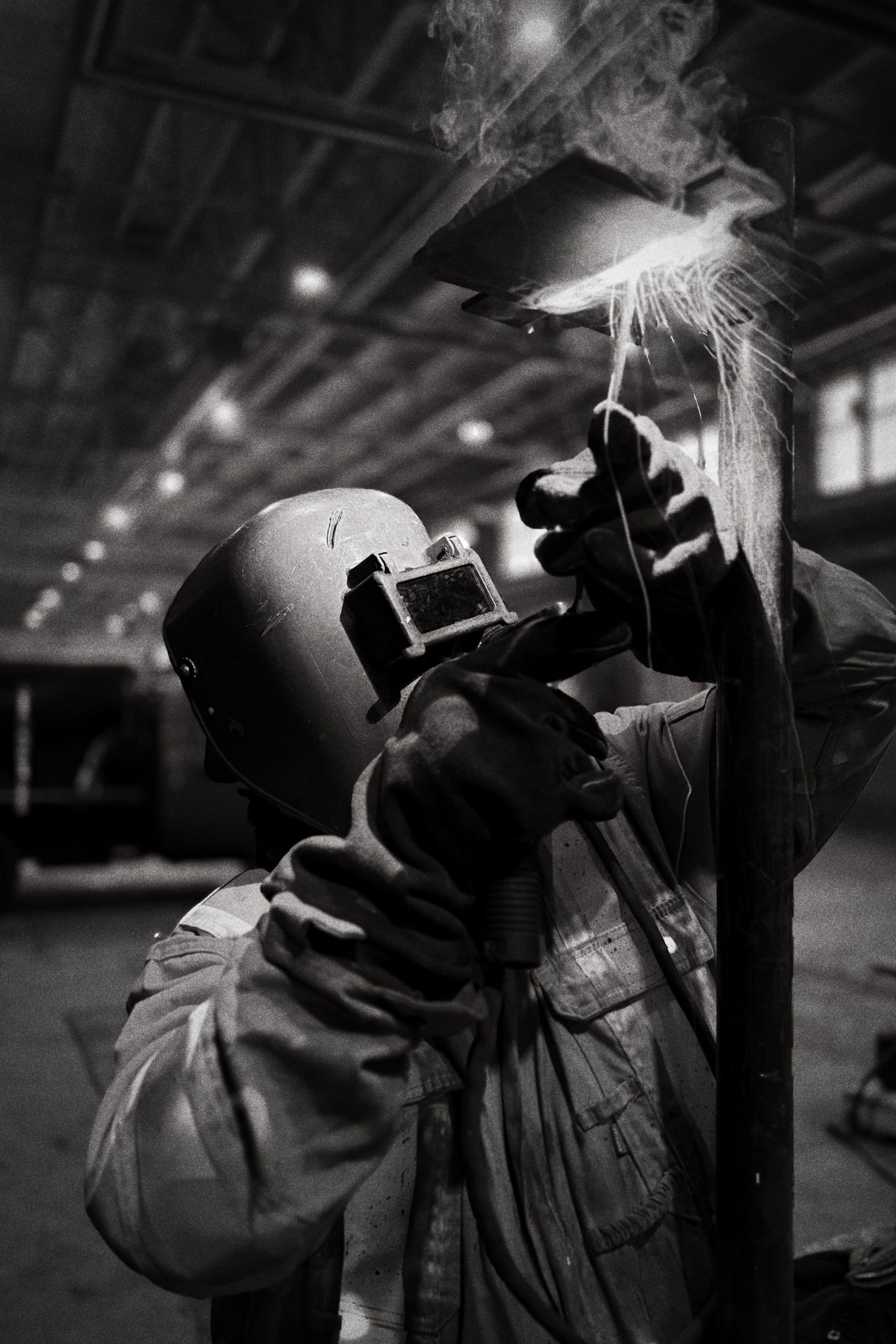 A welder in a protective helmet working inside an industrial facility