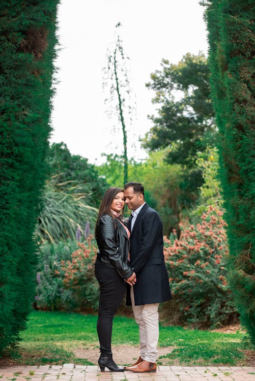 A couple standing between two Thuja trees