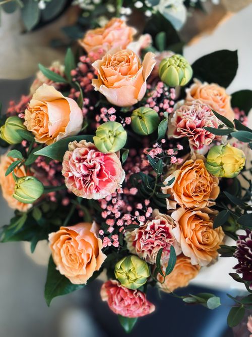 Free Top view of a colorful bouquet featuring roses and carnations with green foliage. Stock Photo