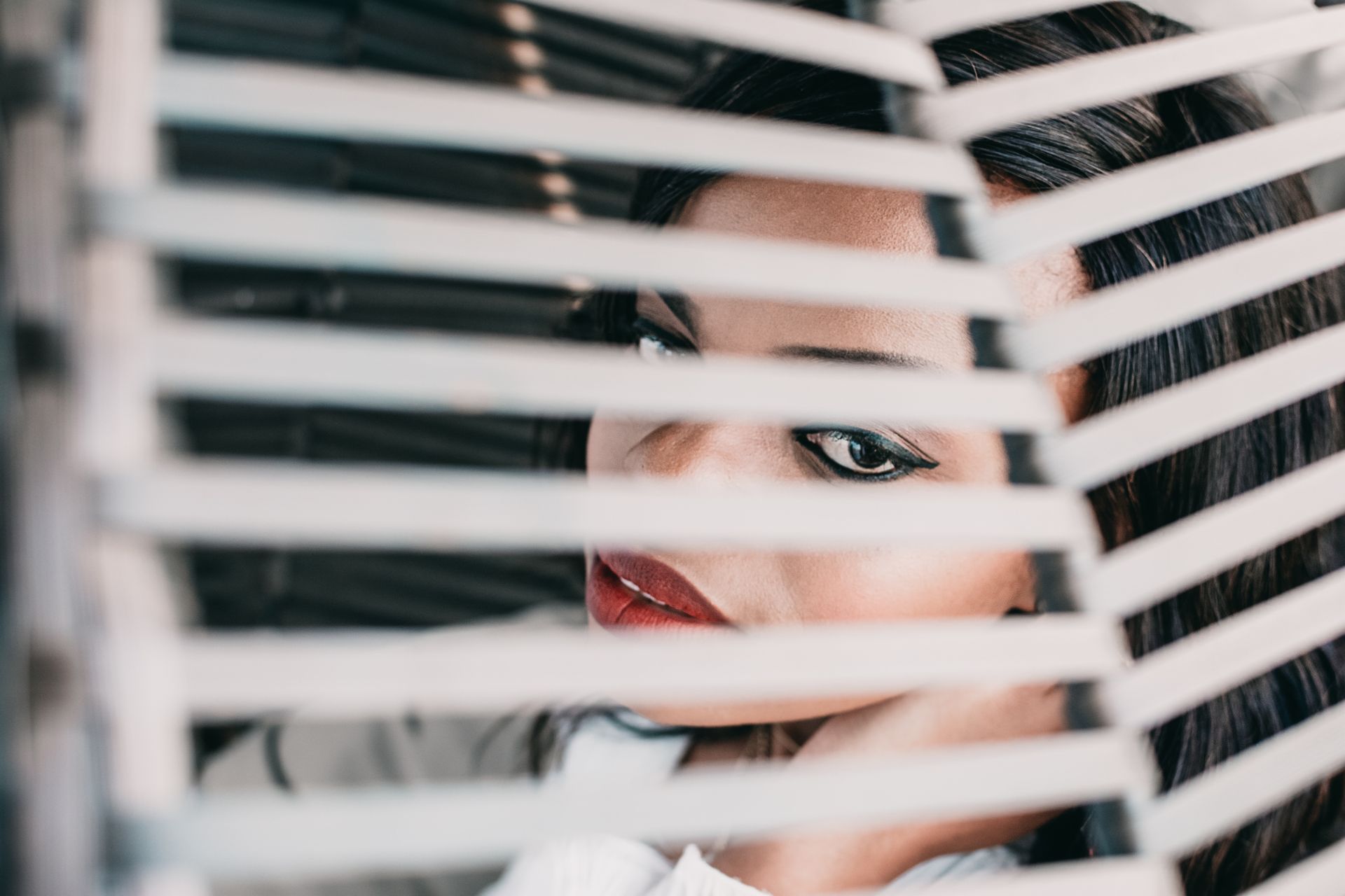 Woman in White Shirt Behind White Window Blinds