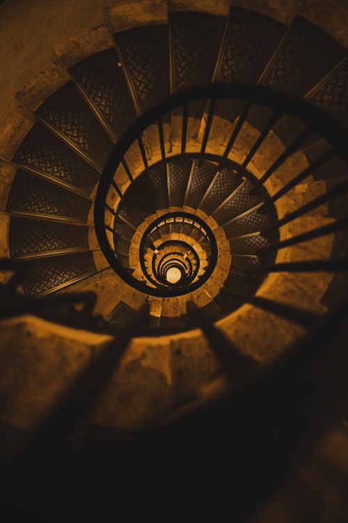 Free Captivating spiral staircase in warm lighting, showcasing geometric elegance and architectural beauty. Stock Photo