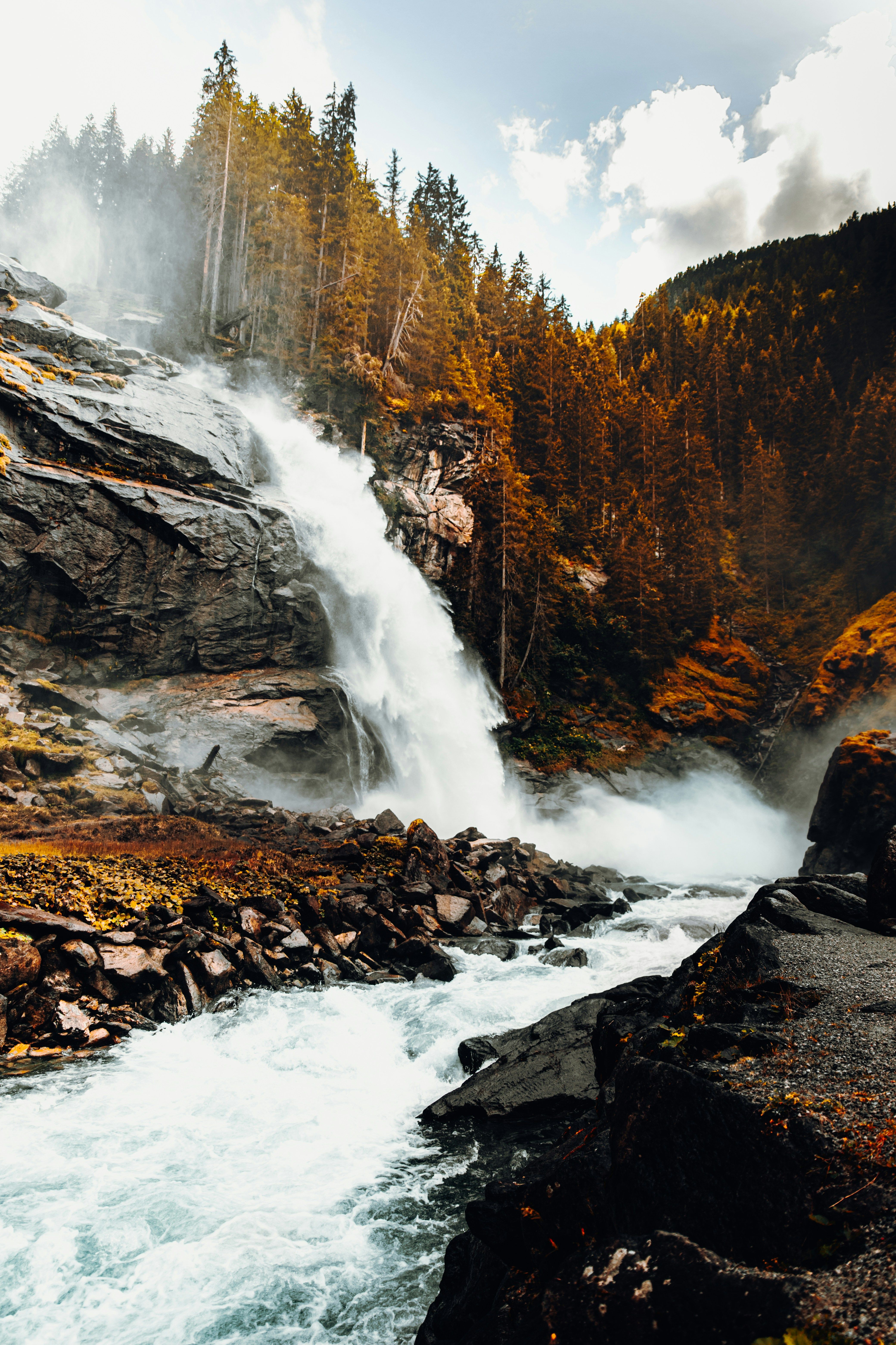 Stunning view of Krimml Waterfall cascading amidst autumn foliage in Salzburg, Austria.
