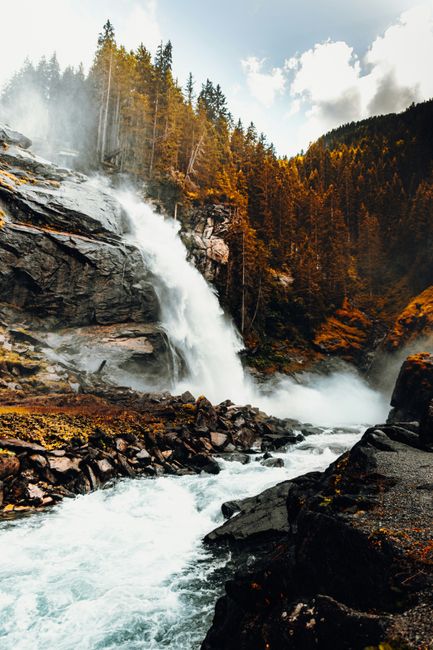 Stunning view of Krimml Waterfall cascading amidst autumn foliage in Salzburg, Austria.