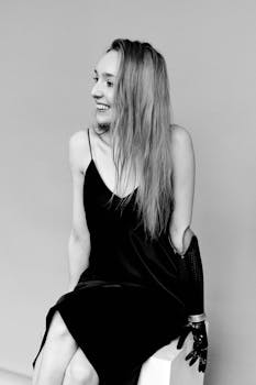 一张单色照片中，一位身着黑色连衣裙、戴着假肢的快乐女人，散发着自信与温暖