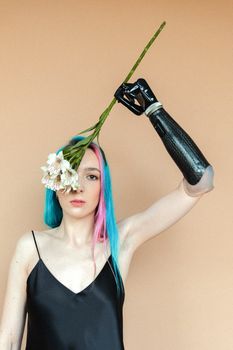 Woman with colored hair and prosthetic arm holding flowers, embracing diversity.