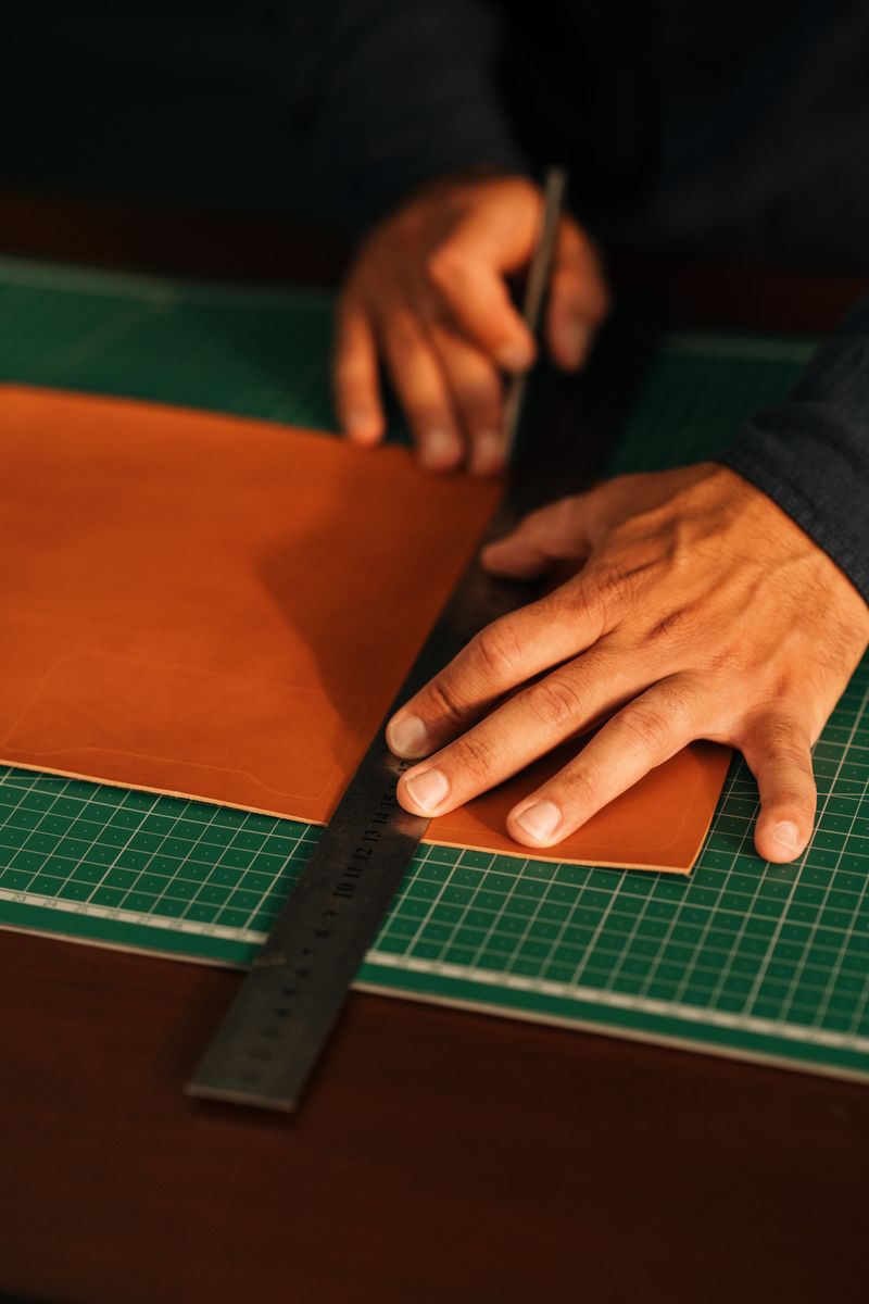 Hands cutting a leather panel on a work mat — Gul Isik on Pexels