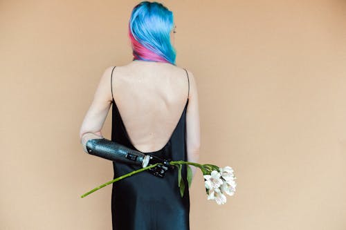 白い花を保持している黒いスパゲッティストラップドレスの女性