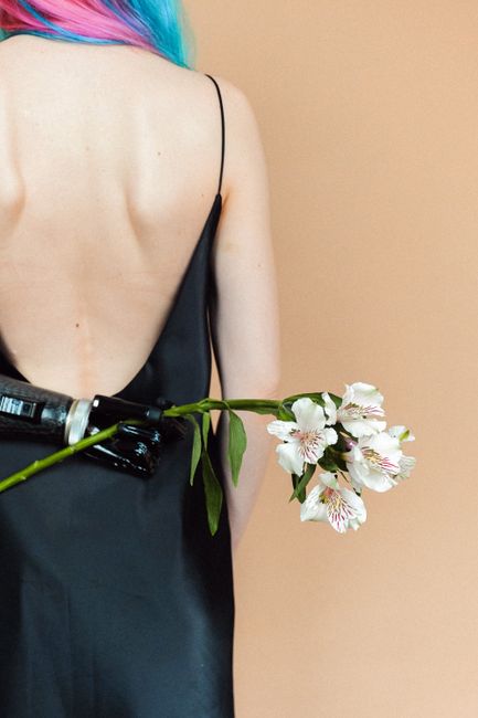 Artistic photo of a woman with colored hair holding a flower with a prosthetic arm, showcasing elegance and diversity.