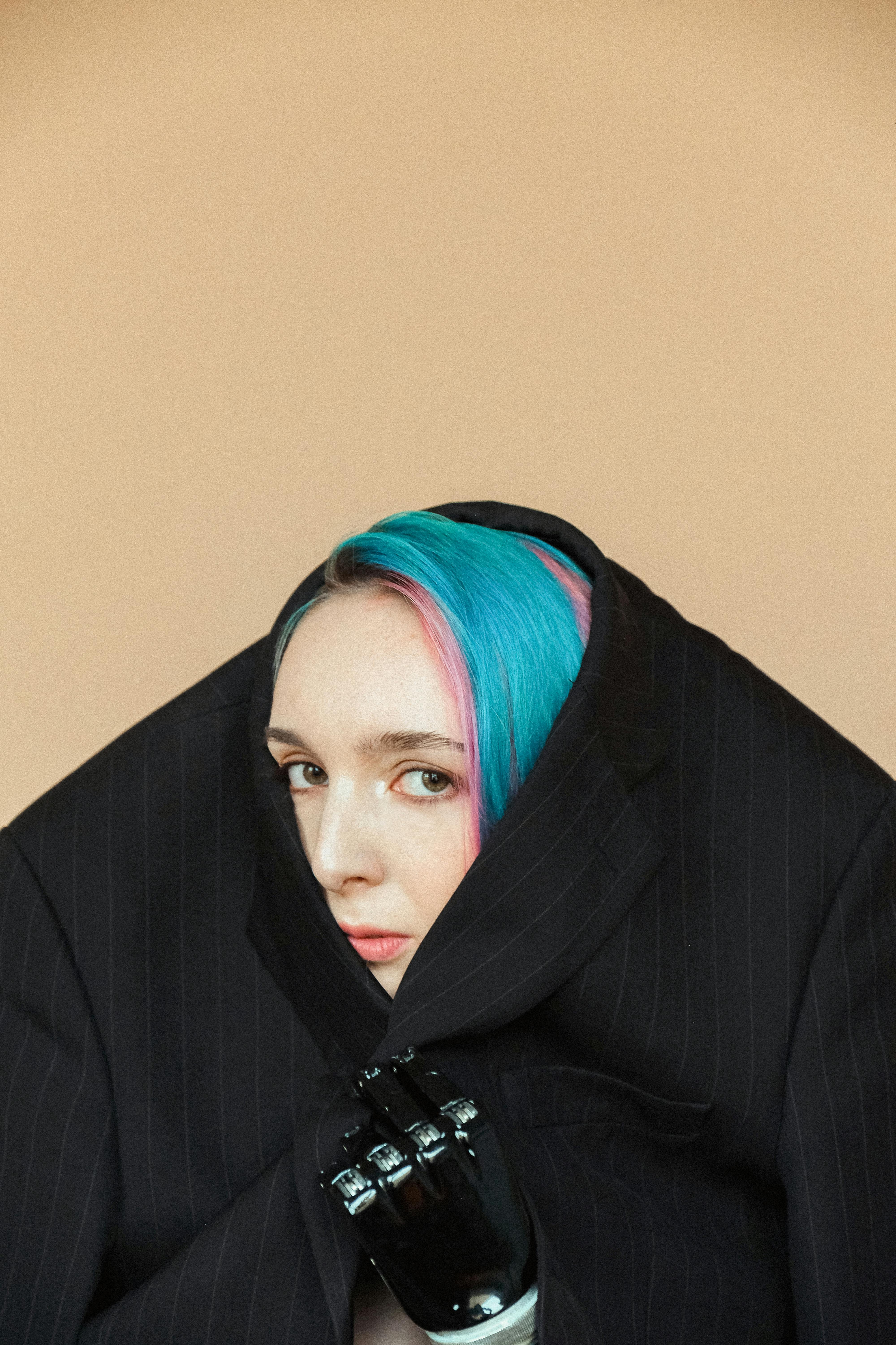 一位蓝发假肢女子的艺术肖像从一件宽大的西装外套中探出头来