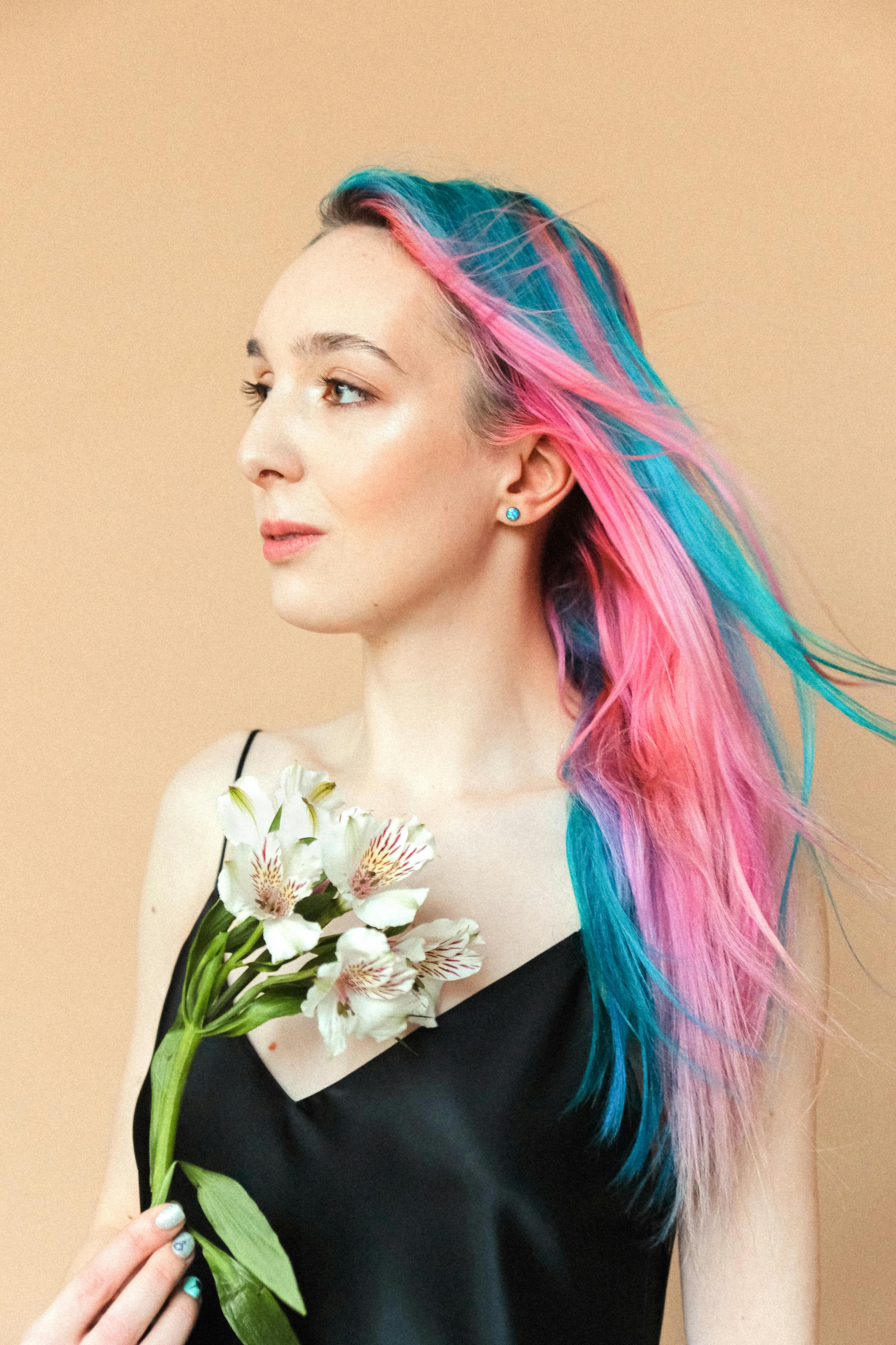 一位女子肖像，她有着充满活力的粉红色与蓝色头发，手持白花