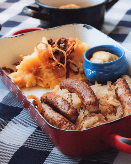 Free Delicious German bratwurst with sauerkraut and fried onions on a rustic table setting. Stock Photo