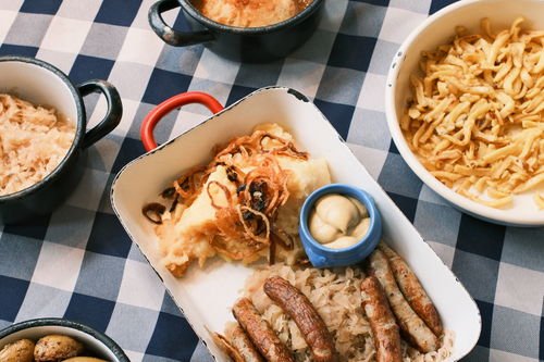 Free A delicious Bavarian meal featuring sausages, sauerkraut, and potatoes on a checkered tablecloth. Stock Photo