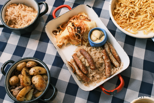 Free German feast with sausages, sauerkraut, potatoes, and noodles on a checkered tablecloth. Stock Photo