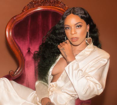 优雅的女人身着缎子长袍，时尚地坐在室内的复古椅子上