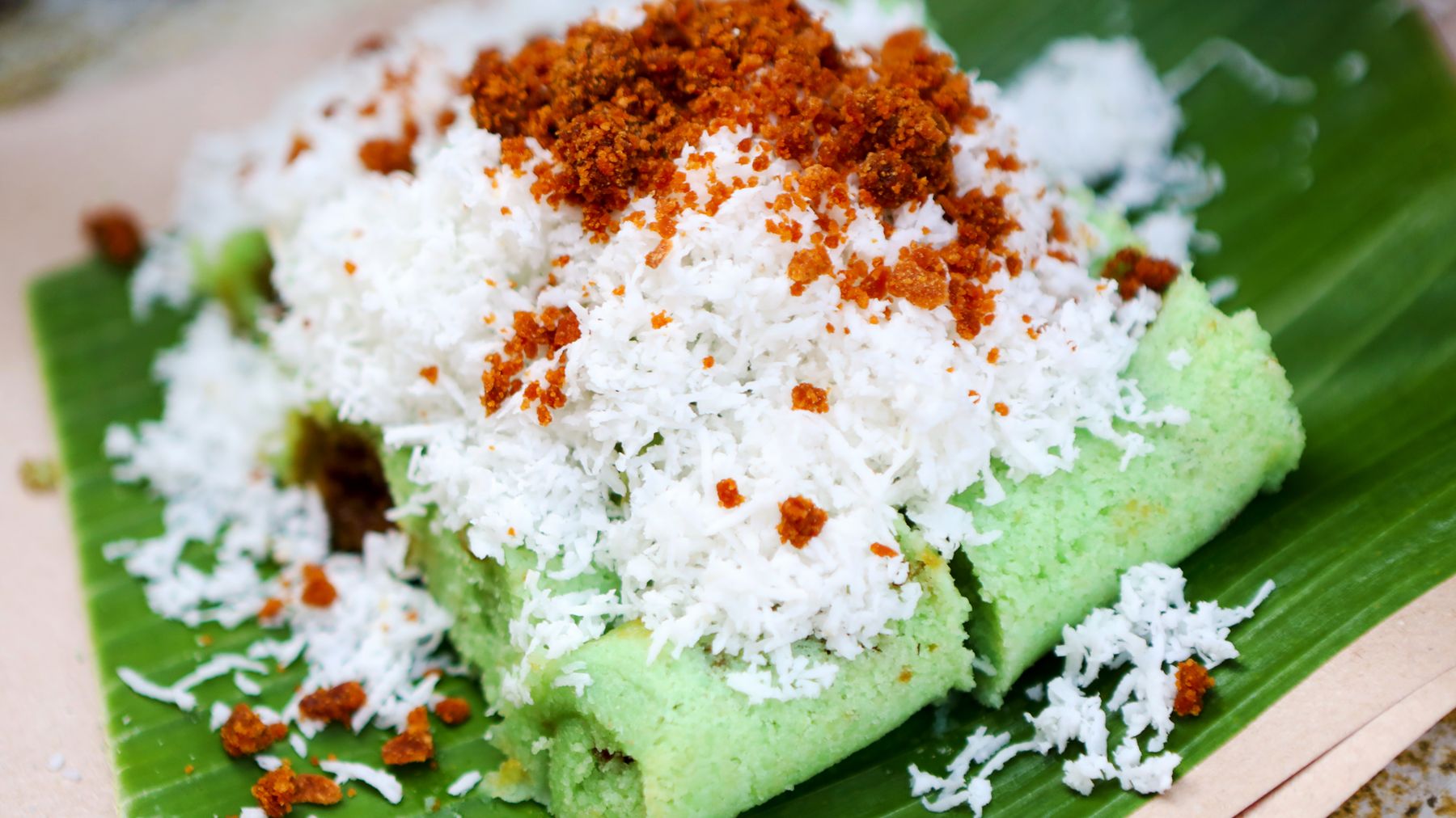 Cận cảnh bánh Putu của Indonesia với dừa và đường trên lá chuối.