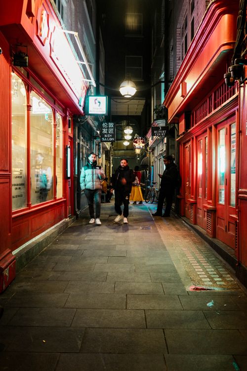 Free A bustling evening scene in London's Chinatown with people walking by colorful storefronts. Stock Photo