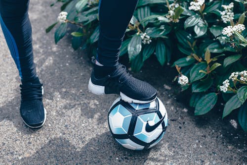 검은 색 바지를 입은 사람과 축구를 밟는 흑백 Nike 축구 클리트