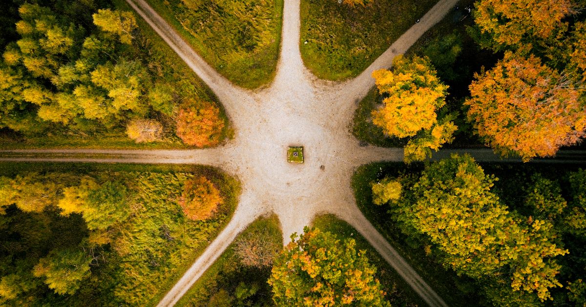 Aerial view of a forest road intersection with vibrant autumn foliage