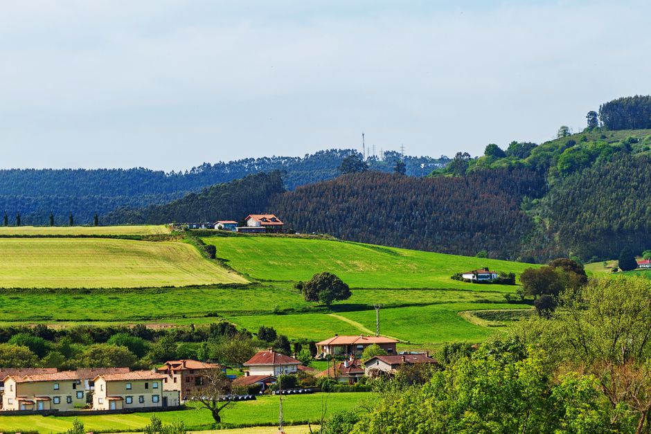 Hermosas colinas verdes con granjas y casas dispersas bajo un cielo despejado.
