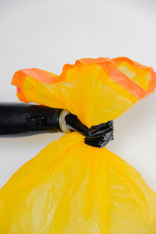 Free Close up of a prosthetic hand holding a colorful plastic bag, symbolizing environmental concern. Stock Photo