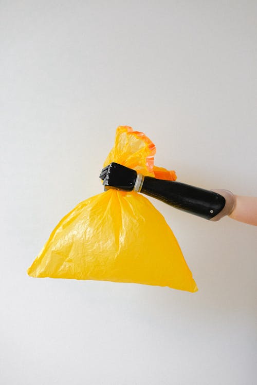 Persona Che Tiene Il Sacchetto Di Plastica Giallo Con Una Mano