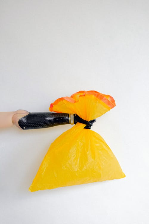 Orang Memegang Kantong Plastik Kuning Dengan Satu Tangan