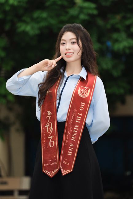 A young woman in Vietnam celebrates her graduation with a smile and a victory gesture.