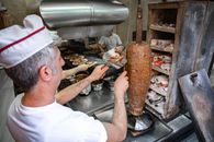 A chef skillfully slices döner kebab in a Bursa kitchen, capturing a slice of Turkish culinary tradition.
