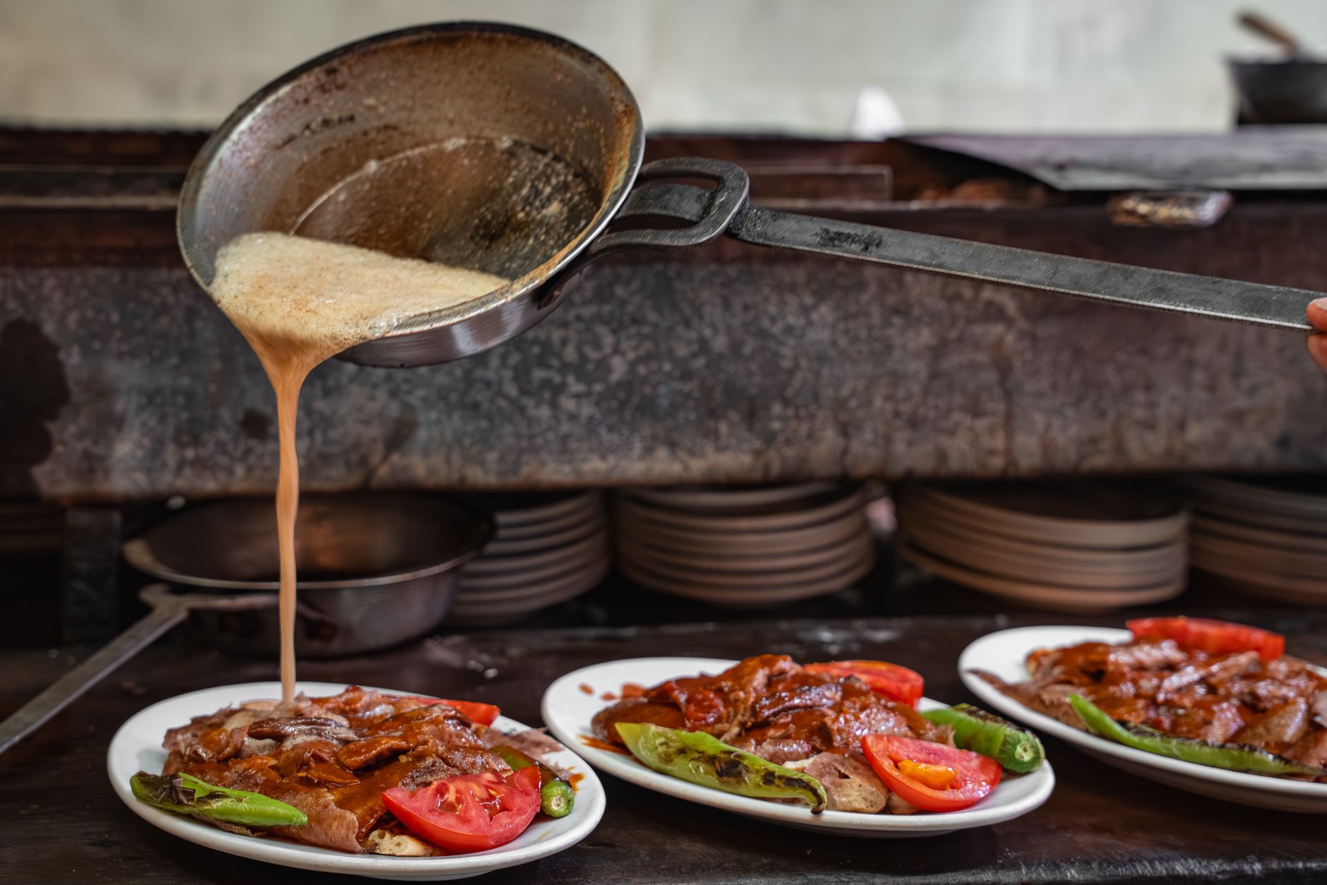 Authentic Iskender kebab with sauce being served on plates, capturing Turkish culinary art.