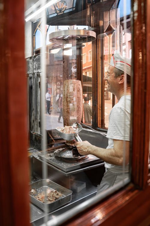 Free Street food vendor in Bursa, Türkiye, expertly slices döner kebab in a classic window stall. Stock Photo