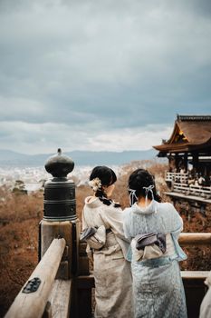 Two women in kimonos admiring the view from Kiyomizu-dera, Kyoto, Japan.