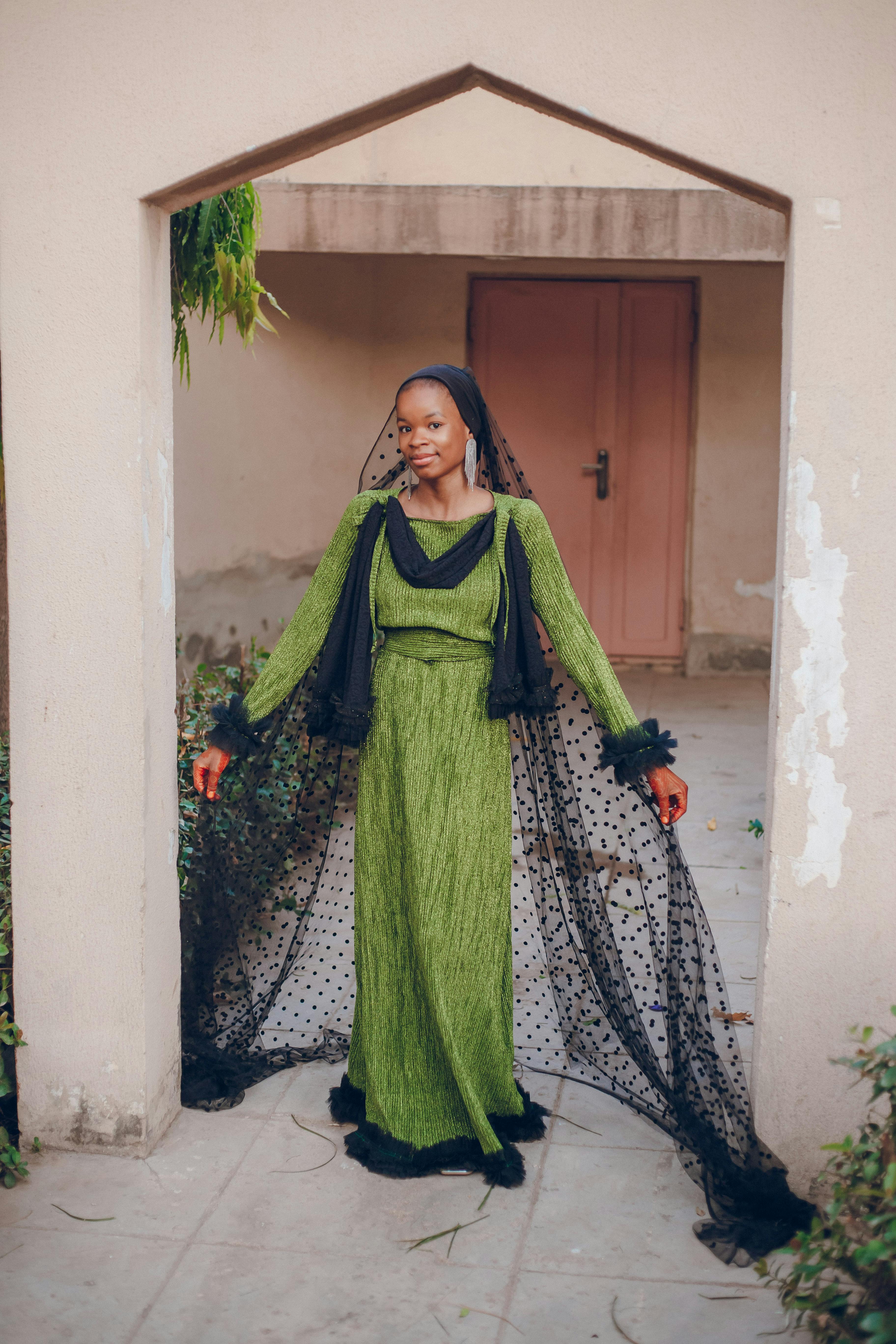 Woman in a stylish green dress with black accents posing indoors.