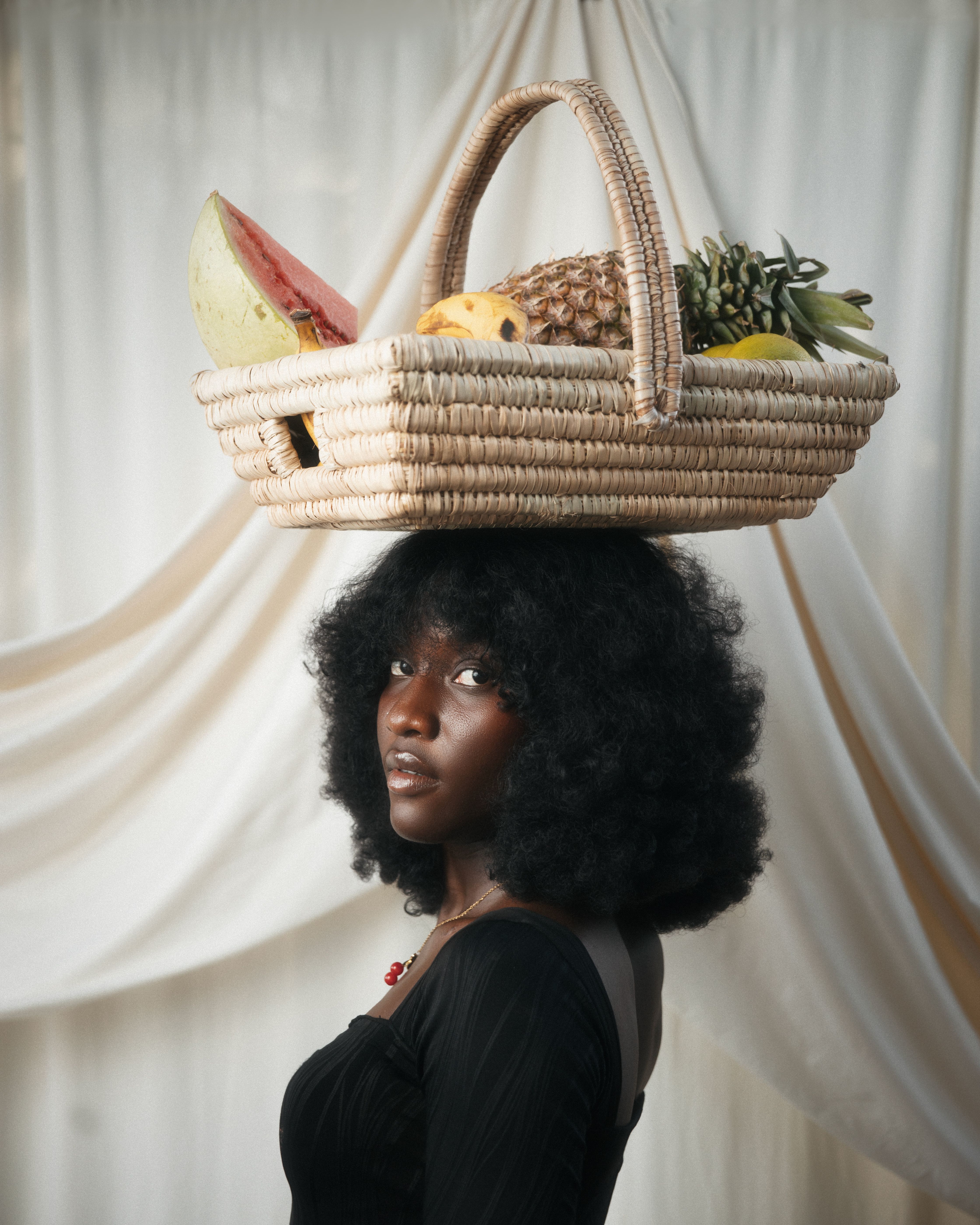 African Woman Balancing Fruit Basket Indoors · Free Stock Photo