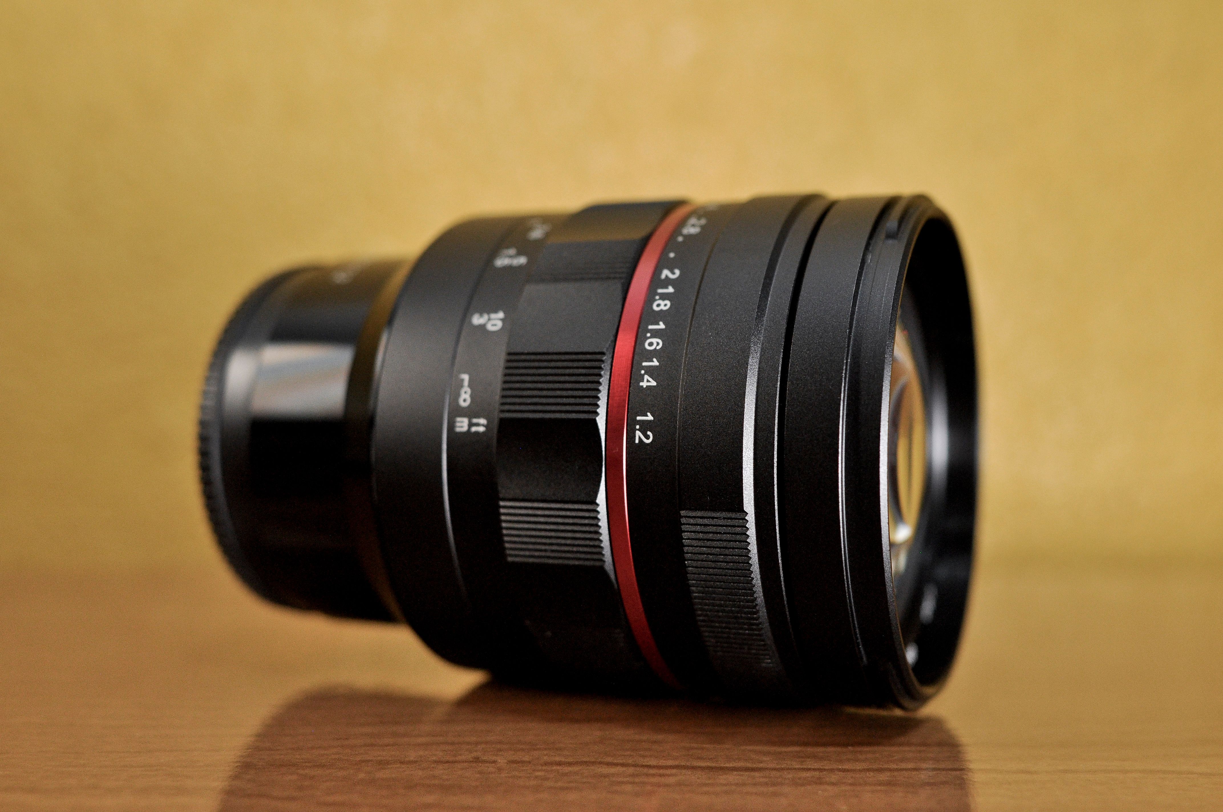 Detailed close-up of a modern camera lens on a wooden surface.