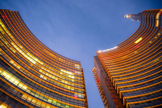 The UniCredit Tower in Milan showcasing its iconic curved design against the evening sky.