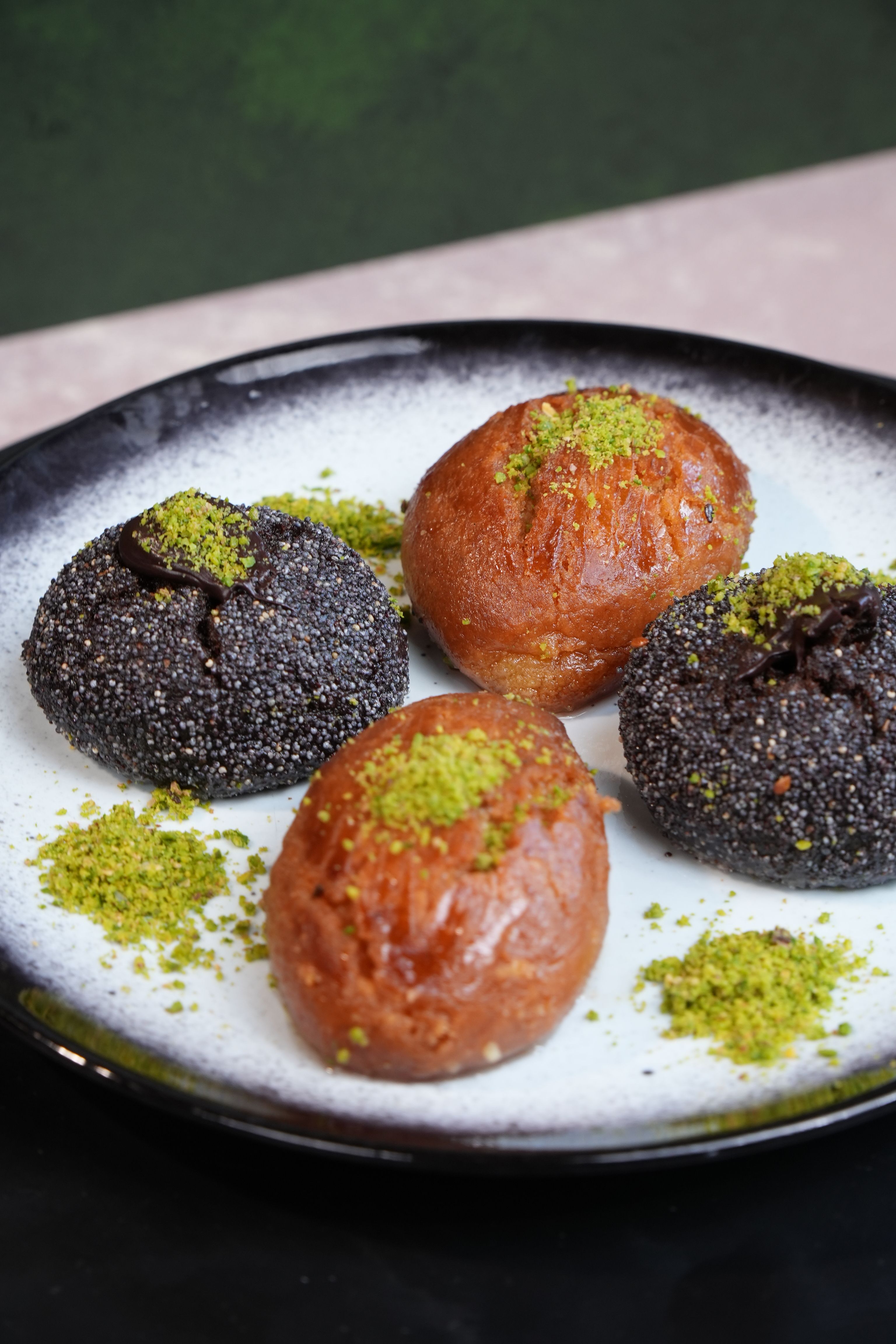 Close-up of Turkish pastries topped with pistachios on a white plate.