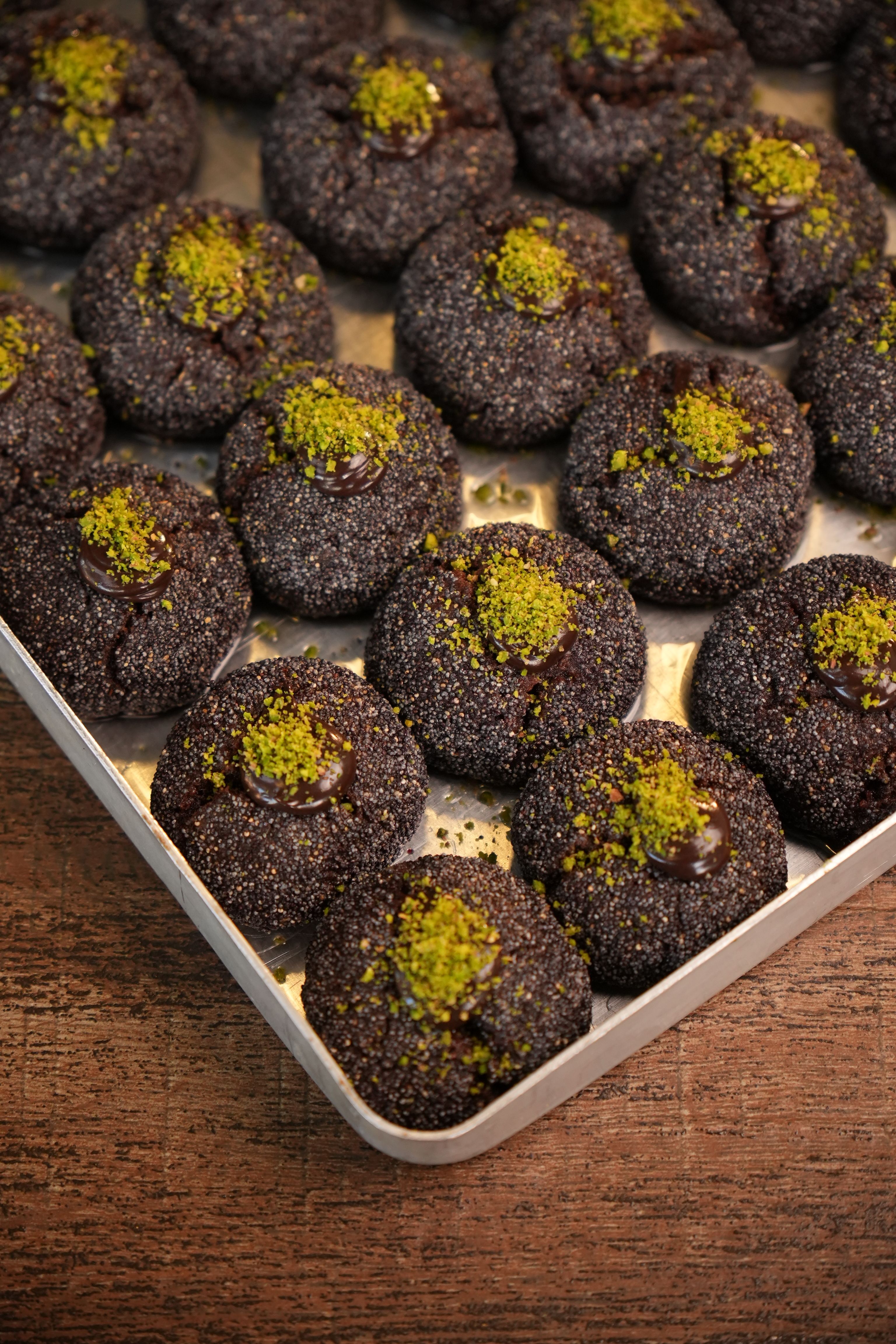 A tray of delicious chocolate cookies garnished with crushed pistachios, perfect for dessert lovers.