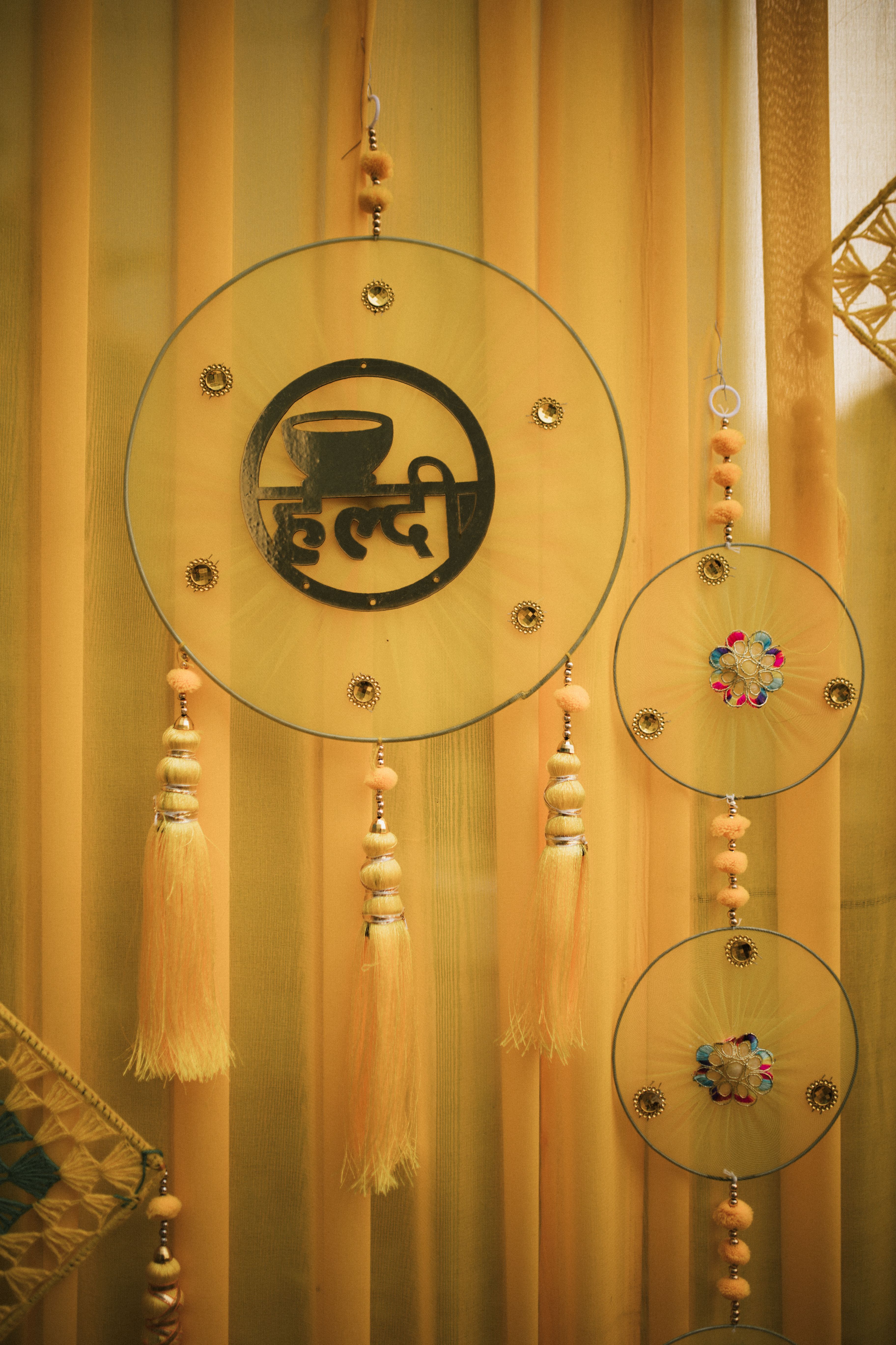 Colorful embroidered dreamcatchers and tassels for a traditional Haldi ceremony.