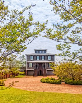 A picturesque Southern-style house surrounded by vibrant spring foliage and brick pathways.